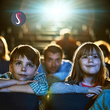 Deux enfants souriant regardant un film au cinéma