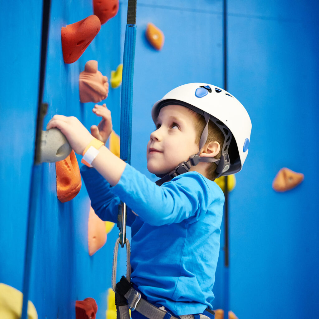 Enfant qui fait de l'escalade avec des protections