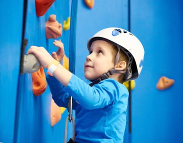 Enfant qui fait de l'escalade avec des protections