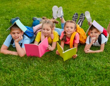 Quatre enfants qui travaillent couchés sur l'herbe